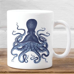 May include: A white ceramic mug with a blue octopus illustration. The octopus has eight tentacles and is depicted in a vintage style.