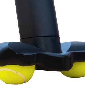 May include: A black walker glide attachment featuring two bright yellow tennis balls secured into a molded plastic base. The device is designed to fit onto the bottom of a walker leg, with the tennis balls providing a smooth surface for movement.