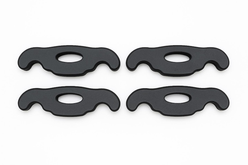 May include: A set of four identical black matte components, each featuring a symmetrical, curved silhouette with a central oval cutout and two downward-facing hook-like extensions on either side, arranged in a two-by-two grid formation.