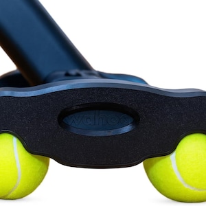May include: A black plastic base component featuring the embossed text wahoo, designed with two circular cutouts that securely hold two bright yellow tennis balls with white seams, attached to a black angled support arm extending upwards.