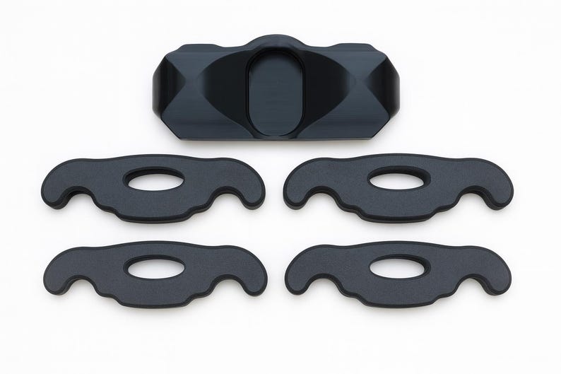 May include: A set of five black components consisting of one central rectangular piece with a smooth, contoured surface and four identical flat, wing-shaped pieces, each featuring a central oval cutout and curved, symmetrical ends.