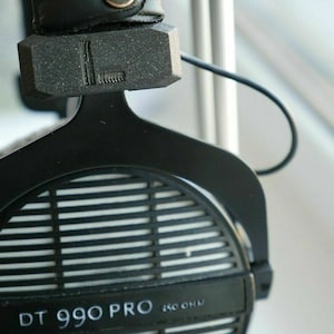 Puede incluir: Auriculares negros con una rejilla plateada y el texto "DT 990 PRO 250 OHM" en el lateral.
