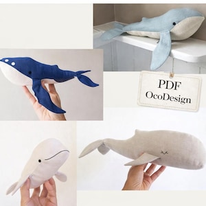 May include: A collection of handmade whale plush toys in various shades of blue and off-white. The whales have simple, stitched details and are made of soft fabric. One tag reads "PDF OcoDesign".