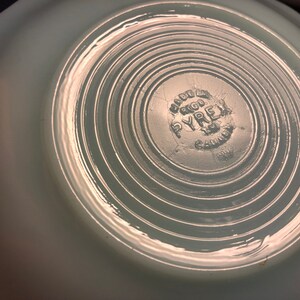 K&ouml;nnte beinhalten: Eine hellblaue Pyrex-Sch&uuml;ssel mit einem kreisf&ouml;rmigen, konzentrischen Ringmuster auf dem Boden. Die Sch&uuml;ssel hat ein "Made in USA"-Etikett mit dem Pyrex-Logo und "Gaffney, S.C." auf dem Boden.