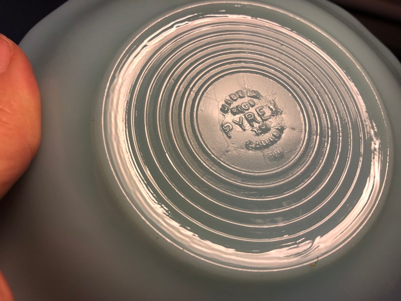 K&ouml;nnte beinhalten: Eine hellblaue Pyrex-Sch&uuml;ssel mit einem kreisf&ouml;rmigen, konzentrischen Ringmuster auf dem Boden. Die Sch&uuml;ssel hat ein "Made in USA"-Etikett mit dem Pyrex-Logo und "Gaffney, S.C." auf dem Boden.