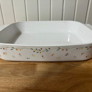 May include: White ceramic baking dish with a floral pattern around the rim. The pattern features small, colourful flowers and green leaves.