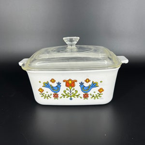 May include: White square baking dish with a glass lid. The dish features a floral design with blue birds and orange flowers.
