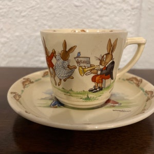 Bunnykins, Royal Doulton, Lambeth Walk and Cycling, filiżanka i spodek Greetings