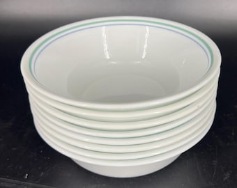 May include: A stack of white ceramic bowls with a blue and green stripe design.
