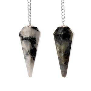 May include: Two gemstone pendulums with silver chains hang against a white background. The pendulums are faceted, with a pointed bottom and a silver cap. One is white and black, the other is gray and black.