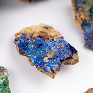 May include: A close-up of a rough, irregular shaped rock with a blue and brown pattern. The rock has a rough, uneven surface and is covered in a layer of blue and brown mineral deposits.