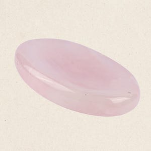 May include: A smooth, oval-shaped rose quartz crystal, polished to a glossy finish. The crystal is a pale pink color with subtle white swirls.