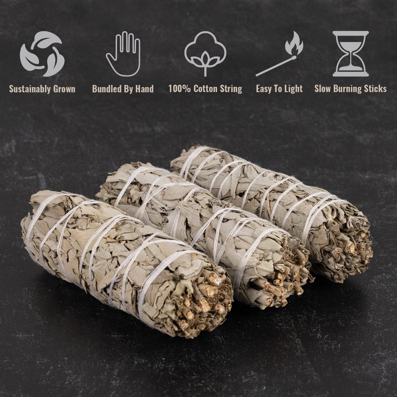 Pu&ograve; includere: Tre bastoncini di salvia bianca legati insieme con uno spago bianco. I bastoncini sono su una superficie grigio scuro. Il testo "Coltivato in modo sostenibile", "Legato a mano", "100% spago di cotone", "Facile da accendere" e "Bastoncini a combustione lenta" &egrave; visibile sopra i bastoncini.