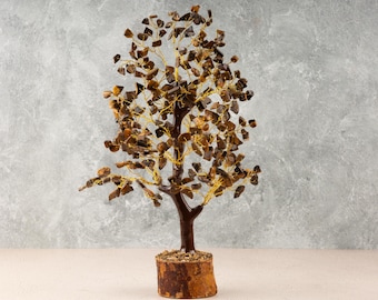 May include: A brown and gold crystal tree with a wooden base. The tree is made of many small crystals that are wired together to form branches. The crystals are a mix of brown and gold colors.