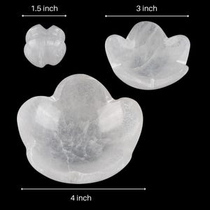 May include: Two white crystal flower-shaped bowls, one measuring 3 inches wide and the other 4 inches wide. A smaller white crystal flower-shaped object measuring 1.5 inches wide is also shown.