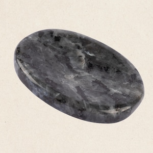 May include: A smooth, oval-shaped black and grey stone with a marbled pattern. The stone is polished and has a smooth, glossy finish.
