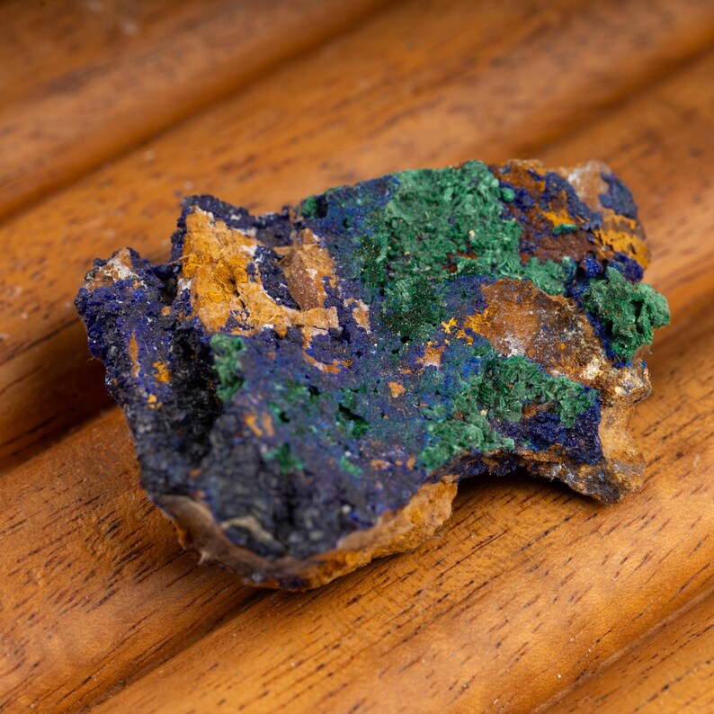 May include: A rough, irregularly shaped rock with a mix of blue, green, and brown colors. The rock has a rough, textured surface and appears to be a natural mineral specimen.