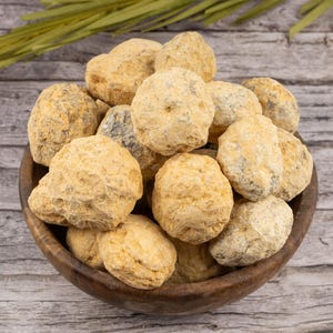 May include: A wooden bowl filled with a variety of light brown geode crystals.