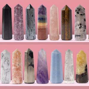 May include: A collection of 20 crystal points in various colors and textures, including amethyst, rose quartz, clear quartz, tiger's eye, and black obsidian. The points are arranged in two rows on a pink surface.