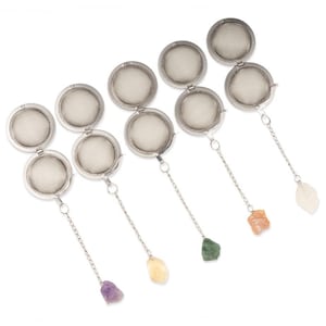 May include: Several stainless steel tea infusers with chain and gemstone accents. Each infuser is round with a mesh basket and a hinged lid. The chains are attached to various gemstones, including amethyst, citrine, green stone, orange stone, and a white stone.
