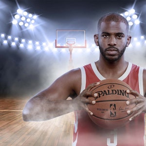 Op de afbeelding: Een basketballer in een rood-wit shirt houdt een bruine basketbal vast met het Spalding-logo. De basketbal heeft het NBA-logo en een handtekening.