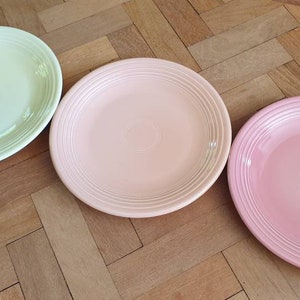 Puede incluir: Tres platos de cena de cerámica en diferentes colores pastel: verde claro, rosa claro y rosa. Los platos tienen un borde ligeramente elevado y un diseño de espiral sutil.
