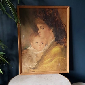 May include: A framed painting of a woman in a yellow shawl holding a child. The woman is wearing a black lace veil and a pearl earring. The painting is in a wooden frame.