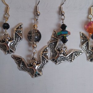 Silver colored bat earrings. Each style sold separately. Please choose, black bead, black crackle bead, color changing beads, orange bead.