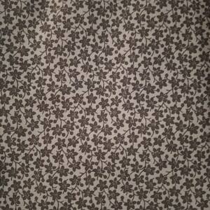 May include: A close-up of a light blue fabric with a repeating pattern of small black flowers. The fabric is measured with a ruler that reads "Made in China".