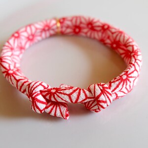 Peut inclure: Un bracelet &agrave; motifs rouges et blancs avec une fermeture nou&eacute;e. Le bracelet pr&eacute;sente un motif g&eacute;om&eacute;trique r&eacute;p&eacute;titif rouge sur fond blanc. Il s'agit d'un accessoire d&eacute;coratif.
