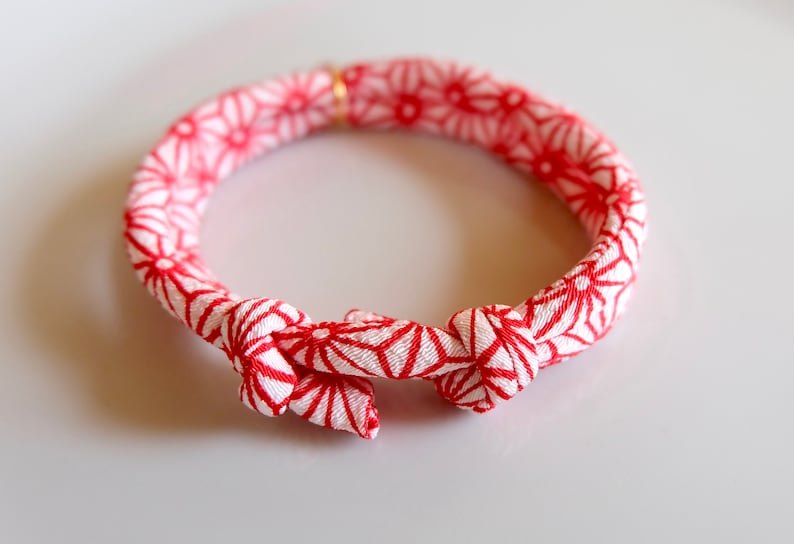 Peut inclure: Un bracelet &agrave; motifs rouges et blancs avec une fermeture nou&eacute;e. Le bracelet pr&eacute;sente un motif g&eacute;om&eacute;trique r&eacute;p&eacute;titif rouge sur fond blanc. Il s'agit d'un accessoire d&eacute;coratif.