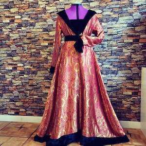 May include: A long, red and gold brocade gown with a black velvet trim and a black velvet sash. The gown has a fitted bodice and a full skirt.