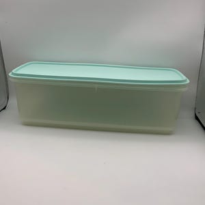 May include: A rectangular storage container with a translucent, semi-clear base and a solid, light mint green lid. The container features a flat, smooth top surface and straight, vertical sides, providing a simple, functional design for storage.
