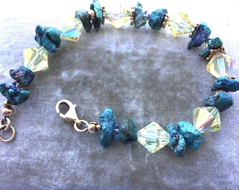 May include: A turquoise and crystal bracelet with a silver clasp. The bracelet features irregular shaped turquoise stones and clear faceted crystals.