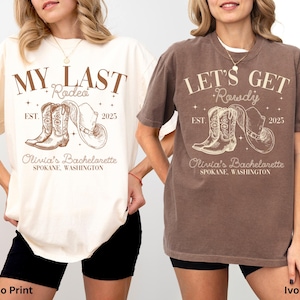 May include: Two t-shirts, one ivory and one espresso, featuring a rodeo-themed graphic. The ivory shirt reads "My Last Rodeo" with boots and a hat, and the espresso shirt says "Let's Get Rowdy". Both shirts include "Olivia's Bachelorette" and "Spokane, Washington".