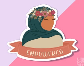 May include: A sticker featuring a woman wearing a green headscarf and a floral crown. The sticker has a red banner with the word "EMPOWERED" on it. The sticker is on a pink and purple background. The text "LITTLE MOON TALES" is in the bottom right corner.
