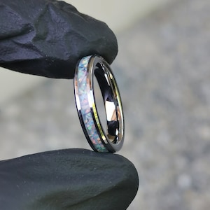 Könnte beinhalten: Ein silberner Ring mit einem dünnen Band und einer weißen Opal-Einlage.