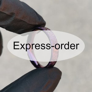 Könnte beinhalten: Nahaufnahme eines lila und silbernen Rings mit einer strukturierten Oberfläche. Der Ring wird von einer behandschuhten Hand gehalten. Der Text "Express-order" ist im Hintergrund sichtbar.