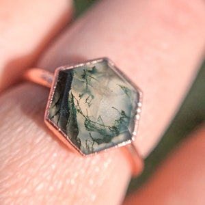May include: A rose gold ring with a hexagonal green moss agate stone.