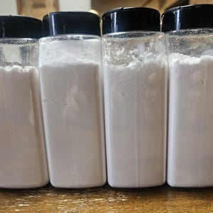 May include: A white ceramic mug with a black handle and the text "But First, Coffee" in a black, bold font. The mug is on a white surface. The mug is 4 inches tall.