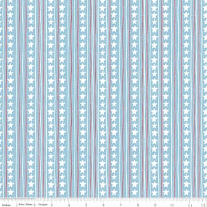 May include: Light blue fabric with vertical stripes of white stars, red lines, and white lines. The fabric has a distressed, textured appearance. The image includes the text "Inches" and "Riley Blake Designs".