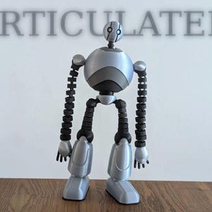 May include: An articulated robot figure with a smooth silver torso, head, and limbs, contrasted by dark gray segmented joints in the arms and legs. The word ARTICULATED is printed in large gray capital letters above the robot's head.
