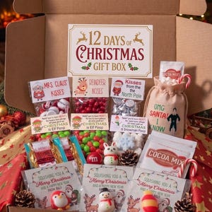 May include: A cardboard gift box labeled 12 Days of Christmas containing assorted holiday treats. Items include bags of candy labeled Mrs. Claus Kisses, Reindeer Noses, and Christmas Elf Poop, a cocoa mix pouch, and small festive character figurines.