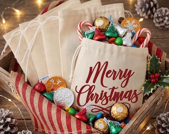 May include: A set of beige drawstring fabric bags, with one bag featuring the red text Merry Christmas, filled with assorted holiday candies including foil-wrapped chocolates, colorful candy-coated chocolates, and red and white candy canes.
