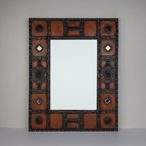 Pu&ograve; includere: Specchio rettangolare con cornice decorativa. La cornice presenta un motivo ripetuto di quadrati e cerchi nelle tonalit&agrave; del marrone e del nero. Piccoli accenti a forma di diamante e specchio quadrato sono incorporati nel design.