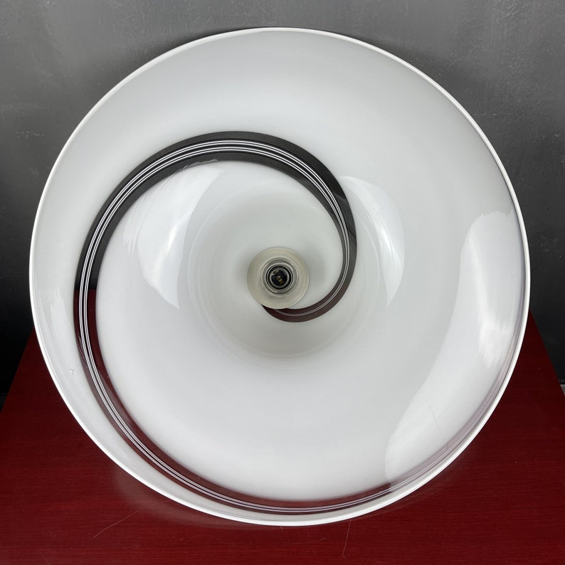 May include: White glass ceiling light fitting with a black spiral design. The light fitting has a white glass shade with a black spiral design.