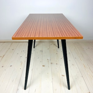 Peut inclure: Une table rectangulaire en bois avec des pieds noirs. Le plateau de table a un motif de grain de bois.