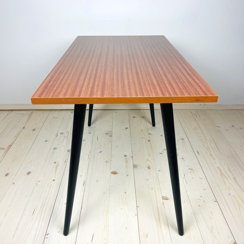 Peut inclure: Une table rectangulaire en bois avec des pieds noirs. Le plateau de table a un motif de grain de bois.