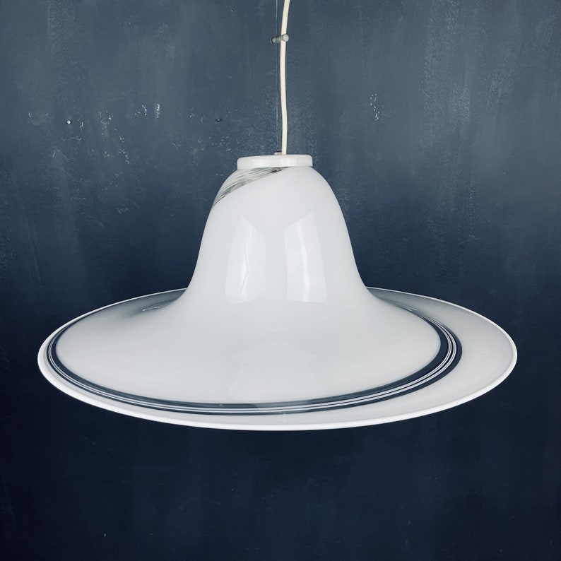 May include: A white ceiling light fitting with a wide, flat, circular base and a bell-shaped shade. The shade has a black and white striped design.