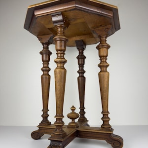 Può includere: Un tavolino vintage in legno con piano ottagonale e gambe tornite ornate. Il tavolo è realizzato in legno scuro e presenta intagli decorativi sulla base. Il tavolo è alto circa 71 cm.